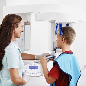 Zahnärztin fertigt digitales Röntgenbild eines Kindes mit moderner Panorama-Röntgentechnik an.